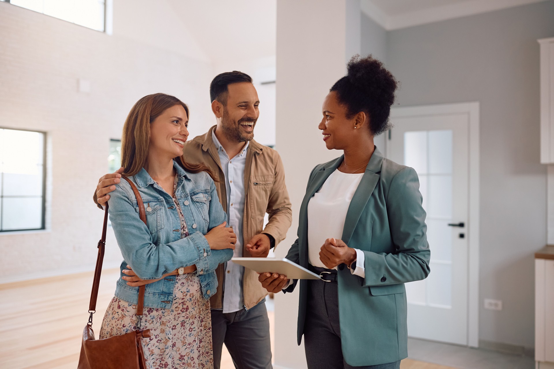 Happy couple and real estate agent using digital tablet during open house day.