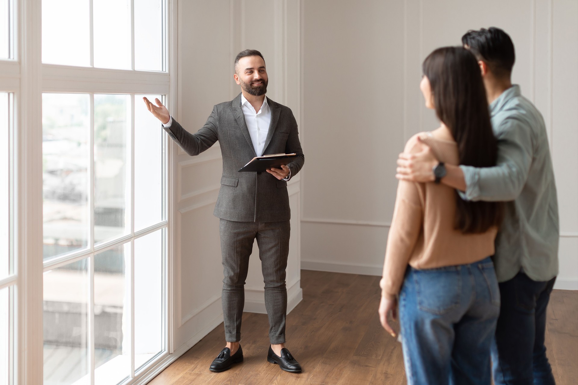 Estate Agent In Suit Showing Buyers New Empty Apartment